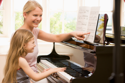Woman and young girl playing piano and smiling